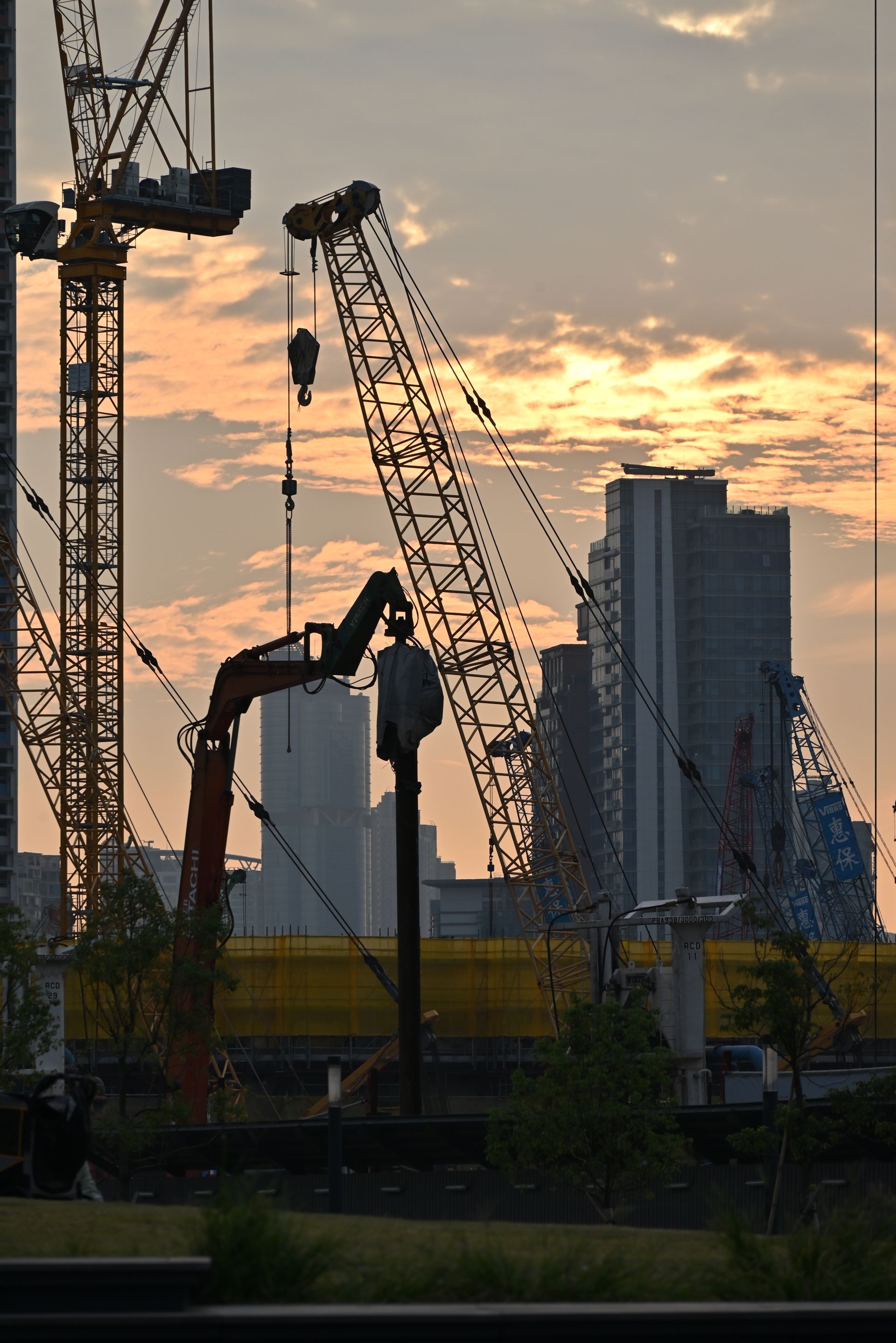 Construction cranes silhouetted at dusk